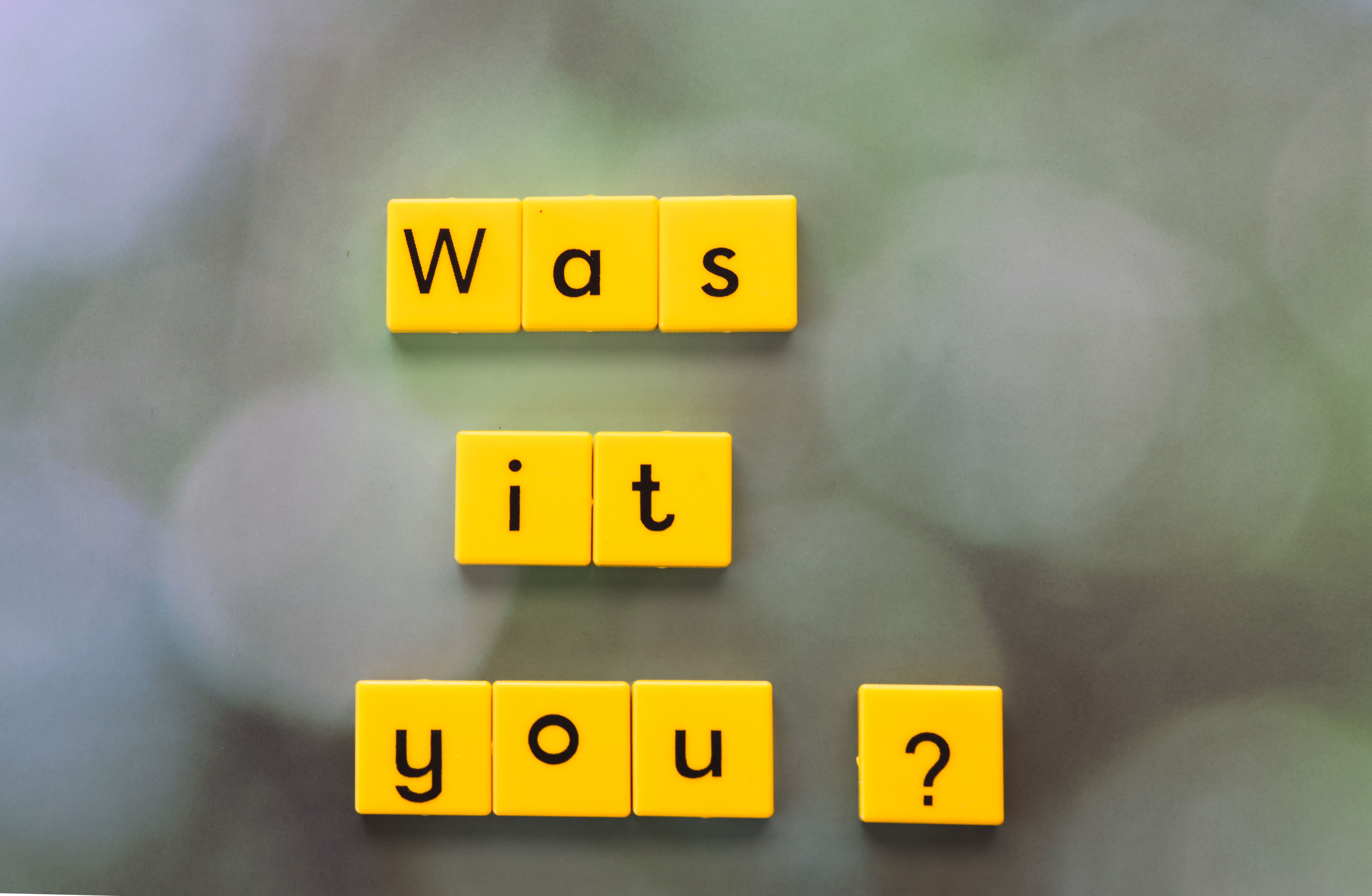 Yellow letter tiles forming the question 'Was it You?' on a blurred green background.